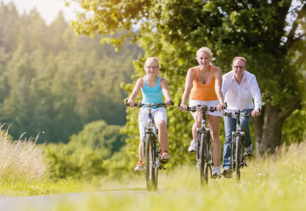Rodzina jadąca na rowerach po leśnej ścieżce w Bieszczadach, w słoneczny dzień