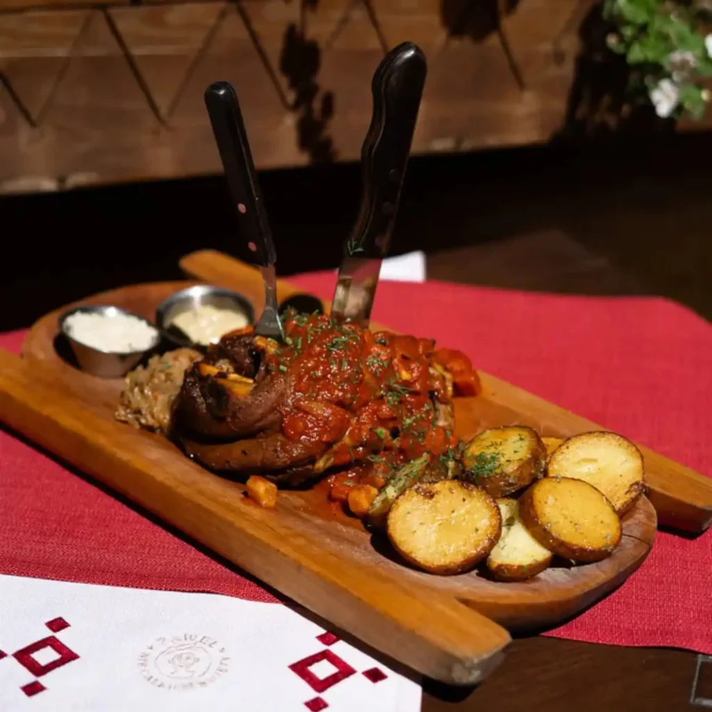 Danie regionalne z Bieszczad: pieczone ziemniaki, gulasz i kapusta podane na drewnianej desce.