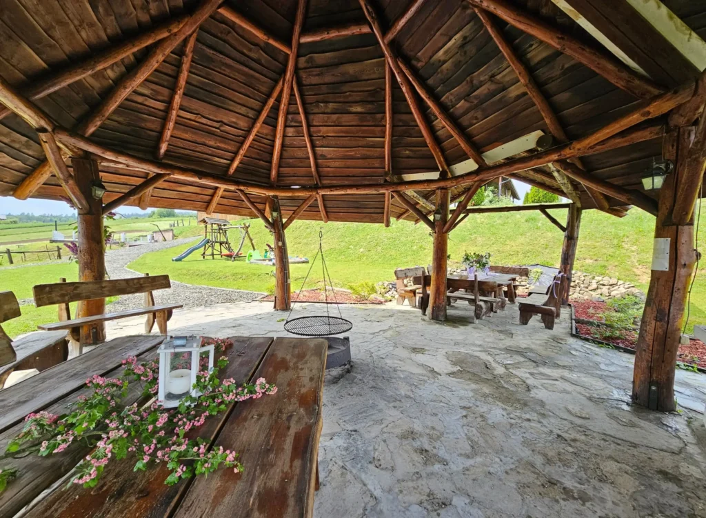 Drewniana chata grillowa z miejscem na ognisko i dużymi stołami, idealna na biesiady w Bieszczadach.