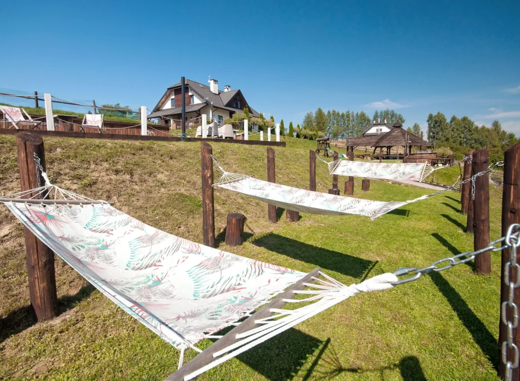 Rząd hamaków rozwieszonych na zielonym wzgórzu w Bieszczadach, doskonałe miejsce na relaks.