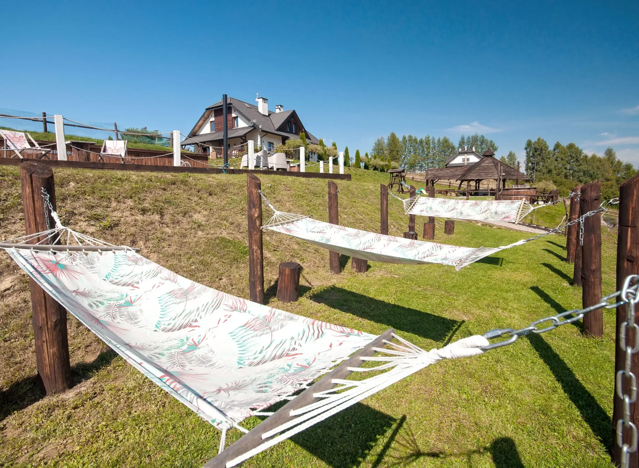 Rząd hamaków rozwieszonych na zielonym wzgórzu w Bieszczadach, doskonałe miejsce na relaks.