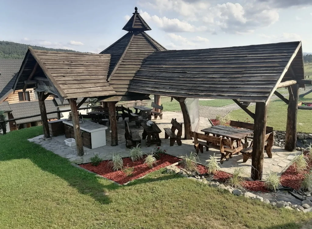 Drewniana chata grillowa w Bieszczadach, z przestrzenią do biesiad na świeżym powietrzu, otoczona zielenią.