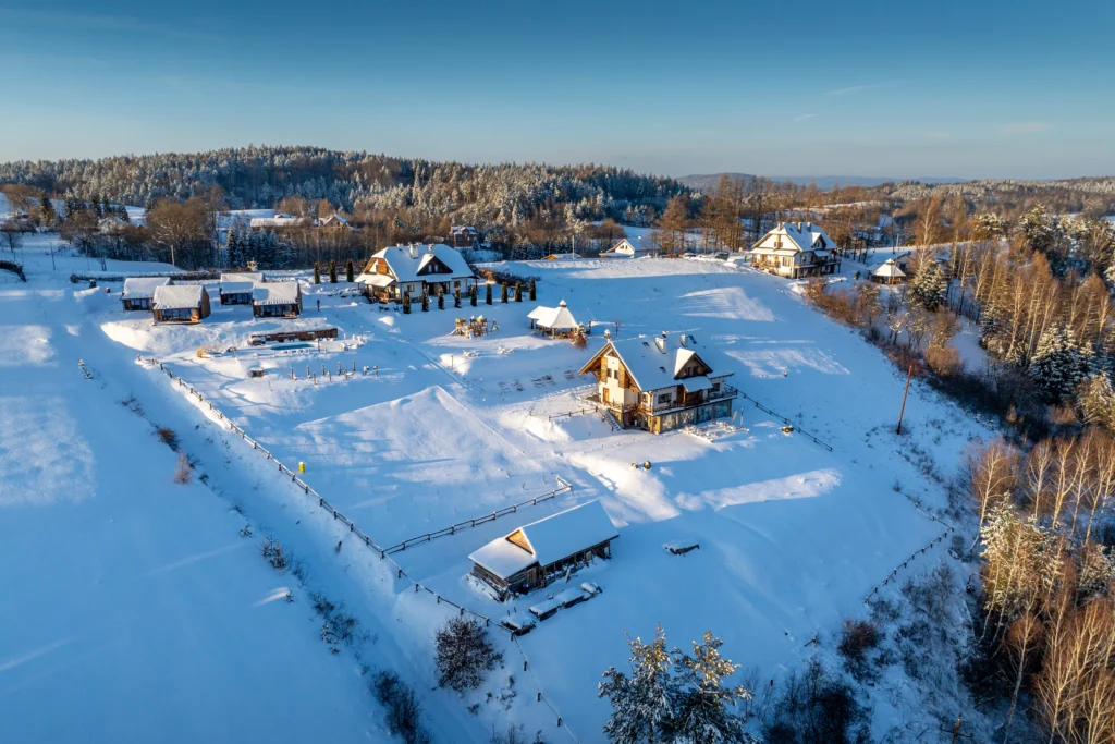 zimowy widok ośrodka z domkami i apartamentami na wzgórzu w Bieszczadach