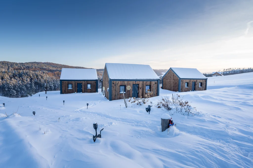 drewniane domki wypoczynkowe zimą na otwartej przestrzeni w Bieszczadach