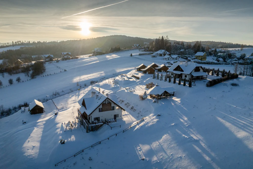 ośrodek wypoczynkowy zimą na tle bieszczadzkich wzgórz o zachodzie słońca