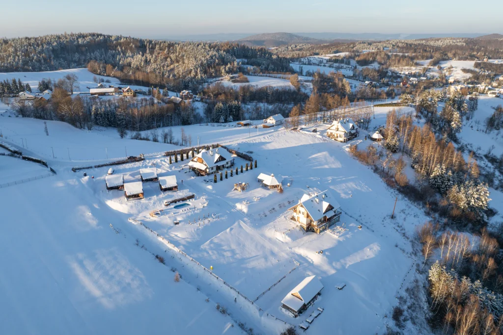 zimowa panorama ośrodka z domkami, apartamentami i placem rekreacyjnym