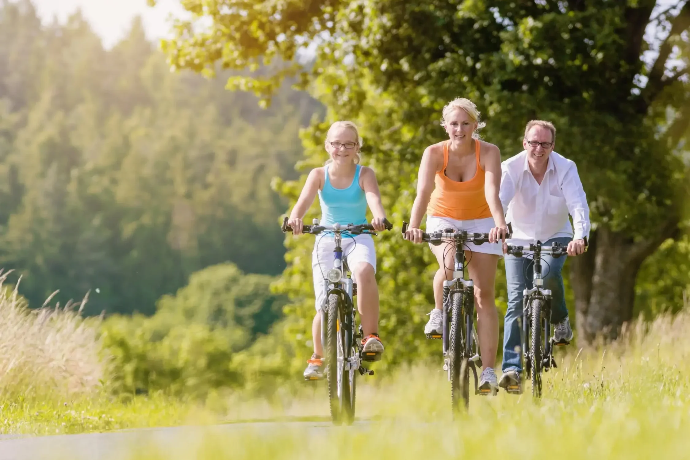 Rodzina jadąca na rowerach po leśnej ścieżce w Bieszczadach, w słoneczny dzień